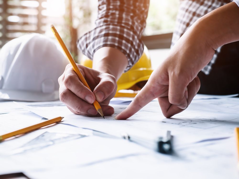 Engenheiros analisando projetos de construção durante a fase de planejamento, um passo fundamental ao financiar apartamento na planta para garantir qualidade.