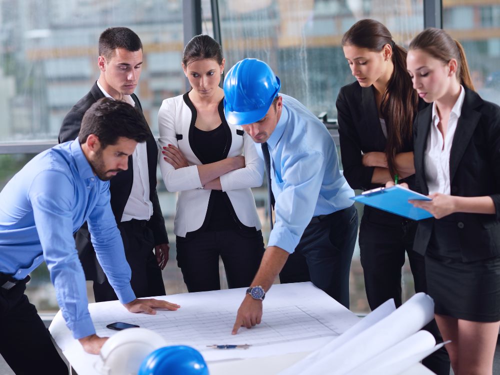Equipe de engenheiros e arquitetos analisando planta de obra, avaliando vistorias e exigências para evitar problemas de morar antes do Habite-se.