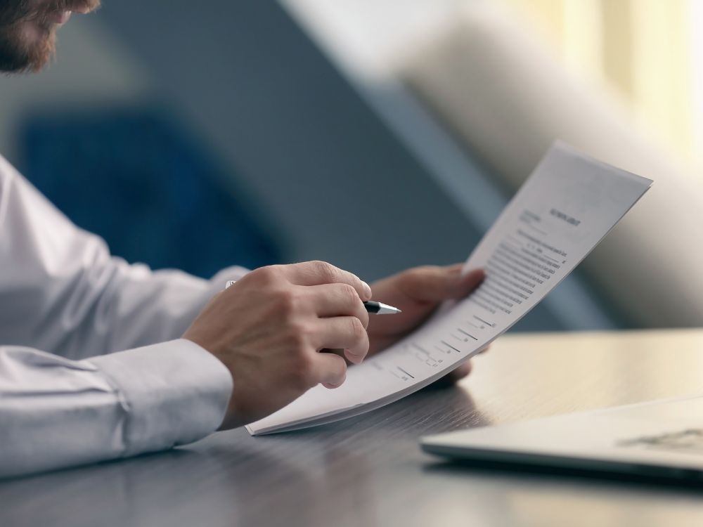 Pessoa segurando contrato imobiliário, analisando documentos necessários para evitar riscos legais ao decidir morar antes do Habite-se.