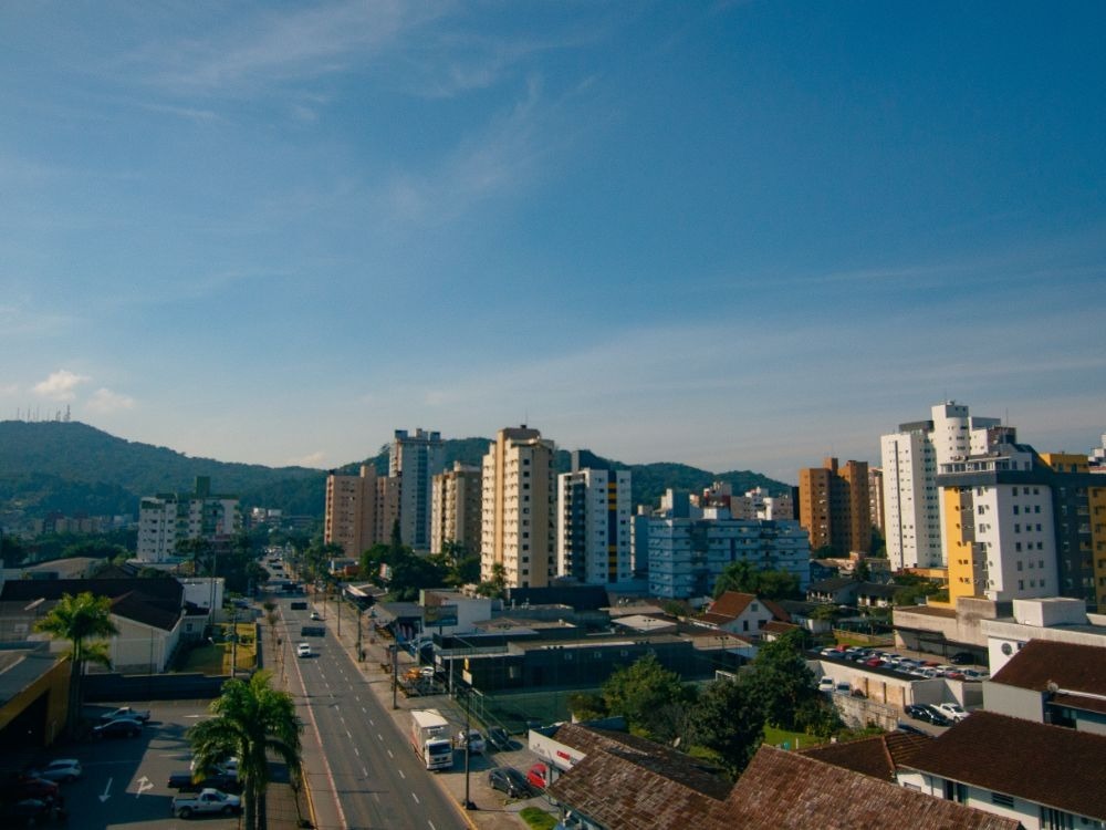 Paisagem urbana dos melhores bairros em Joinville, mostrando avenidas largas, prédios residenciais e montanhas ao fundo.