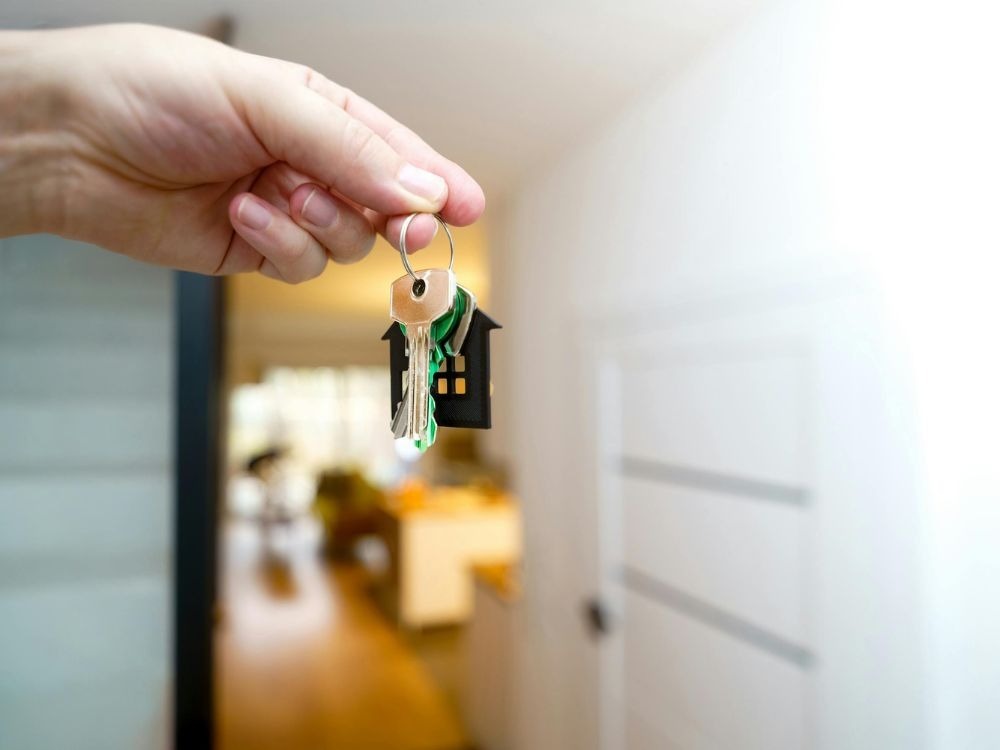 Pessoa segurando chave de imóvel recém-adquirido, simbolizando o sonho realizado ao comprar apartamento para investimento.