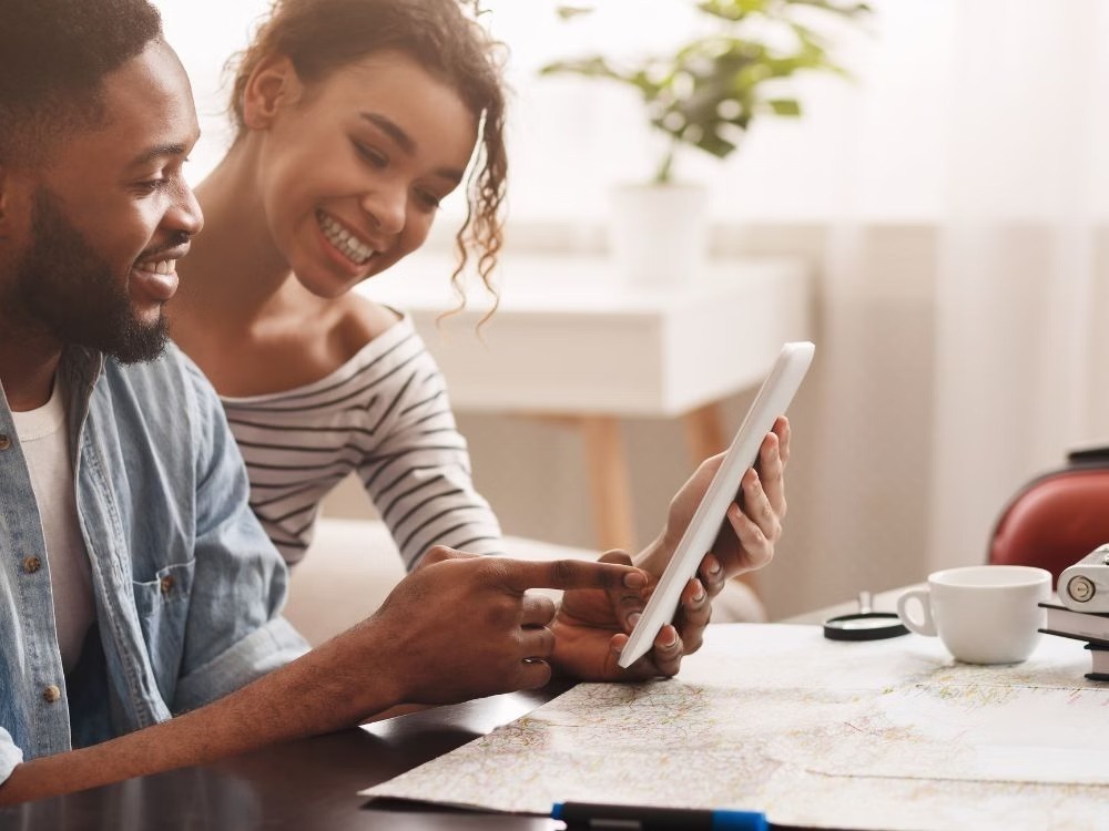 Casal consultando tablet e mapa sobre a mesa, representando o processo de escolha e entendimento de Como usar o FGTS para comprar um imóvel.