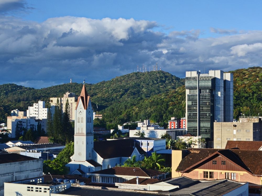 Centro urbano com igreja histórica e prédios modernos ao fundo, cenário que ilustra as Melhores cidades para investir em imóveis.