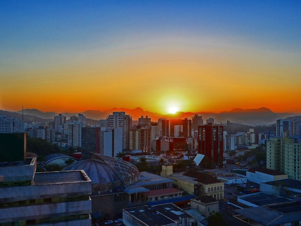 Skyline ao pôr do sol com prédios e infraestrutura consolidada, imagem que destaca as Melhores cidades para investir em imóveis.