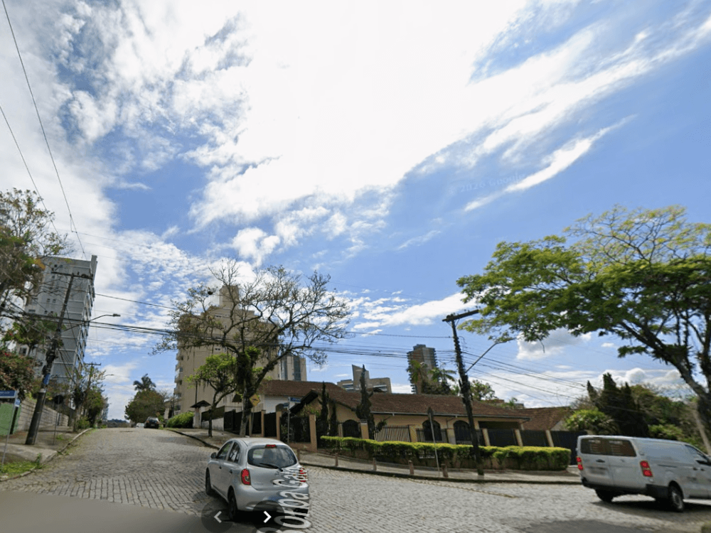 Rua arborizada próxima à Quadra Cultural de Joinville com residências, prédios e infraestrutura urbana consolidada.