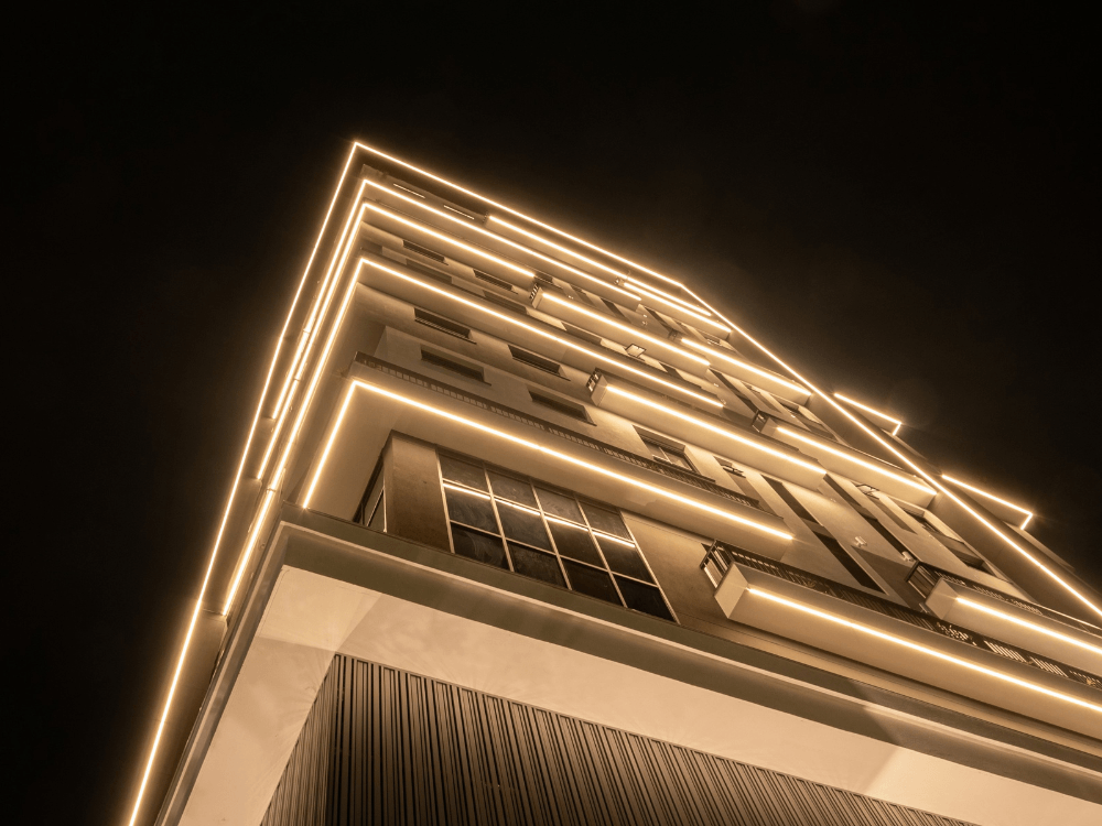 Fachada de edifício residencial moderno iluminada durante a noite, destacando a arquitetura contemporânea em Joinville.
