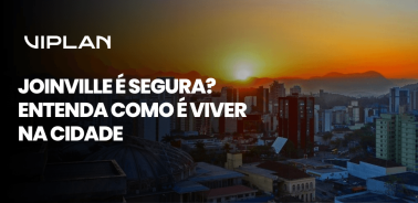 Vista de Joinville ao pôr do sol com prédios e texto Joinville é segura destacando como é viver na cidade.