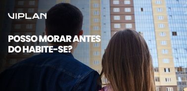 Casal observando prédio recém-construído refletindo sobre os riscos legais e estruturais de morar antes do Habite-se em imóveis sem regularização.